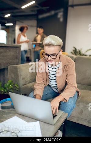 Cheerful young female office worker typing on the laptop Stock Photo
