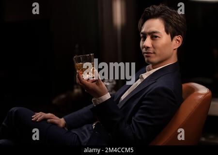 Elegant Chinese man drinking whiskey Stock Photo