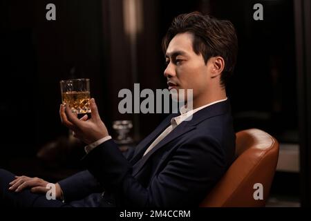 Elegant Chinese man drinking whiskey Stock Photo