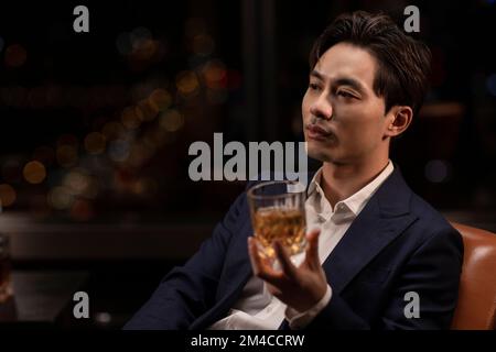 Elegant Chinese man drinking whiskey Stock Photo