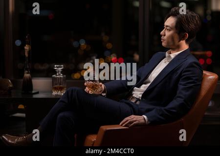 Elegant Chinese man drinking whiskey Stock Photo