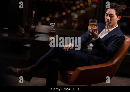 Elegant Chinese man drinking whiskey Stock Photo