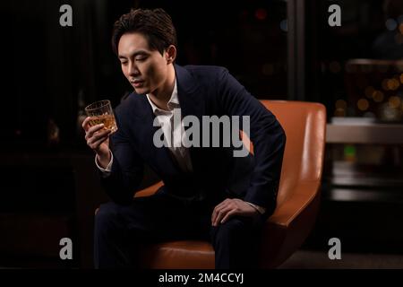 Elegant Chinese man drinking whiskey Stock Photo