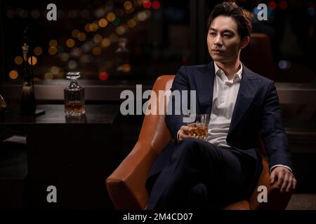 Elegant Chinese man drinking whiskey Stock Photo