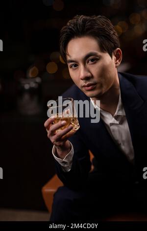 Elegant Chinese man drinking whiskey Stock Photo