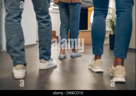 Company of three in a well-lit hallway Stock Photo