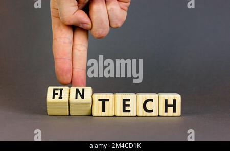 Tech or fintech symbol. Concept word Tech and Fintech on wooden cubes. Businessman hand. Beautiful grey table grey background. Business and tech or fi Stock Photo
