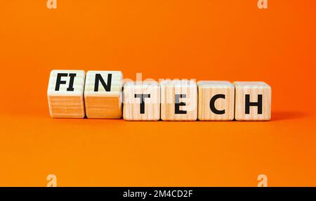 Tech or fintech symbol. Concept word Tech and Fintech on wooden cubes. Beautiful orange table orange background. Business and tech or fintech concept. Stock Photo