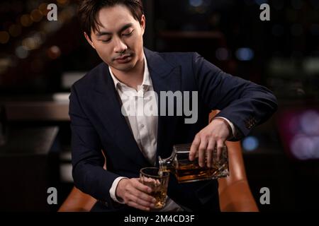 Elegant Chinese man drinking whiskey Stock Photo