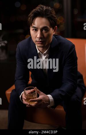 Elegant Chinese man drinking whiskey Stock Photo