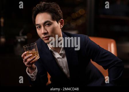 Elegant Chinese man drinking whiskey Stock Photo