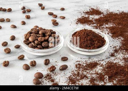 Close-up of a glass cup with coffee beans and another cup with ground coffee Stock Photo