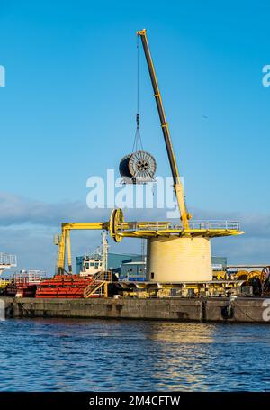 Industrial crane lifting cable wheel on dockside, Leith Docks, Edinburgh, Scotland, UK Stock Photo