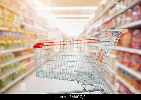 Supermarket aisle with empty shopping cart at grocery store retail business concept Stock Photo