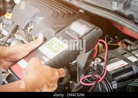 mechanic use voltmeter checking voltage of car battery in car service centre Stock Photo
