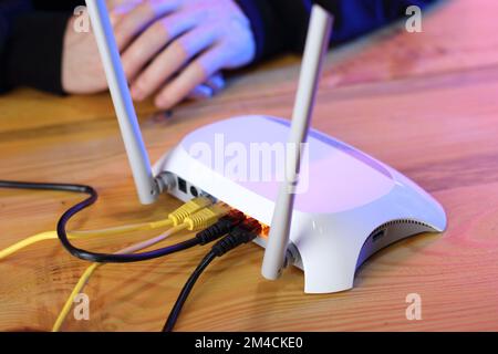 router with connected ethernet cables on table and person's hands Stock Photo