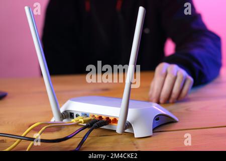 router with connected ethernet cables on table and colored background Stock Photo
