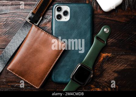 Teal phone on wooden desk with watch and AirPods Stock Photo