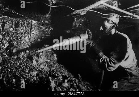 A miner extracting coal by hand with a pneumatic hammer in the ...