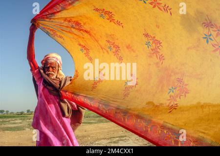 Pilgrim drying his wifes sari after having a bath in the river Yamuna Stock Photo