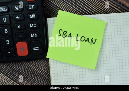 Concept of SBA Loan write on sticky notes with calculator isolated on Wooden Table. Stock Photo