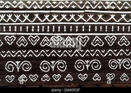 White pattern ornament painting on the dark wood wall in Slovakian old village Cicmany. European history heritage and black and white background conce Stock Photo