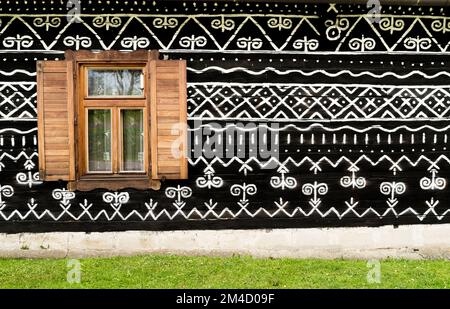 Wooden window on the White and black pattern ornament painting on the dark wood wall in Slovakian old village Cicmany. European history heritage and b Stock Photo