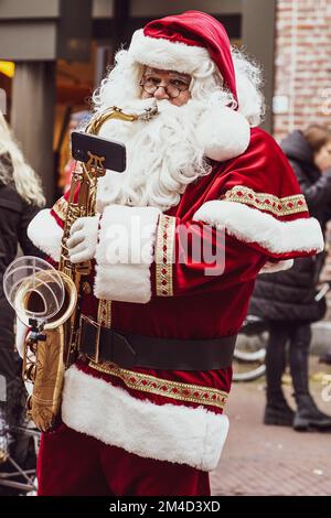 A vertical shot of Santa Claus playing the saxophone in a Christmas Market in Haarlem, the Netherlands Stock Photo