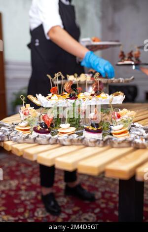 the waiter serves a table with snacks at the buffet. Stock Photo