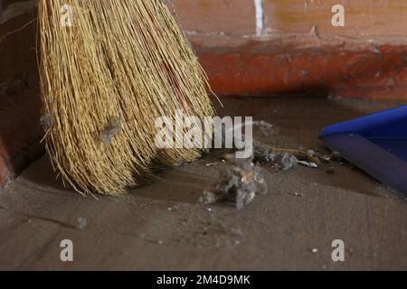 Garbage on the floor in the room. The room has not been cleaned for a long time. Broom and dustpan. Stock Photo