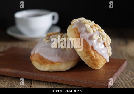 Glazed buns with peanuts and cup of tea on wooden table Stock Photo
