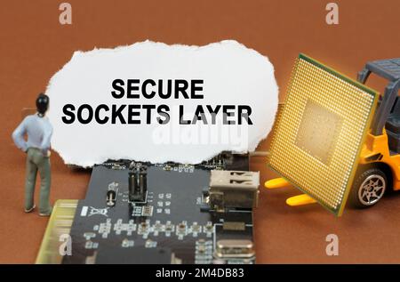Computer concept. On the board with microcircuits lies a paper plate with the inscription - Secure Sockets Layer. Nearby is a toy loader with a proces Stock Photo