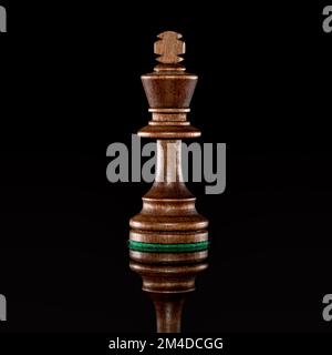 Wooden black chess king isolated at dark background with transparent reflection on the floor Stock Photo