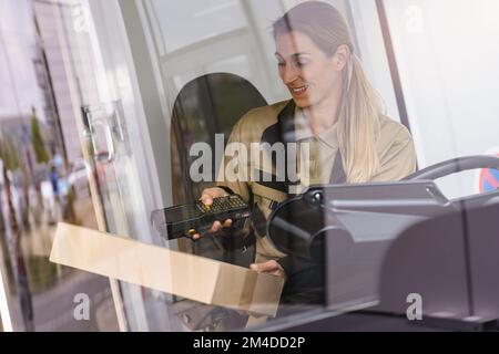 Female delivery driver using barcode scanner checking pacel in a van in the city Stock Photo