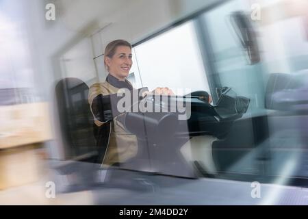 Smiling delivery mwoman sitting in the car as a driver with motion blur Stock Photo
