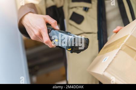 delivery agent scanning barcode with barcode scanner on a parcel during his work shift. Courier Delivery concept image Stock Photo