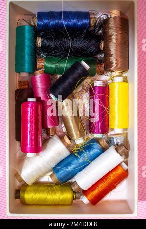 A box with multi colored coins of different threads on a colored background Stock Photo