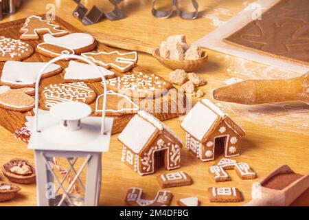 Christmas gingerbread houses and different shaped cookies with sugar icing on wooden table, close up with selective focus Stock Photo