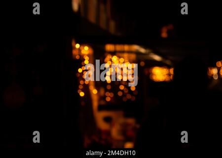 Defocused orange, yellow, black background. Street decoration for Christmas, New Year. Festive garland. City night lights blur bokeh. Holiday abstract Stock Photo