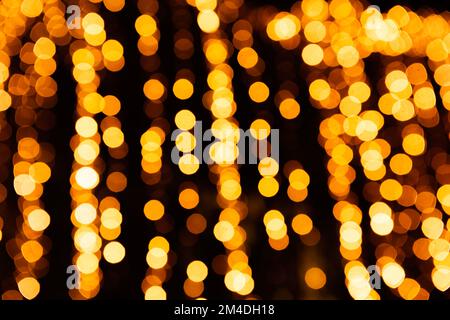 Festive bright blurred golden background. On Christmas black curtain, yellow bokeh lights are shining out of focus. Blank for postcards, place for tex Stock Photo
