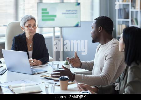 Side view portrait of black man talking to female manager during meeting in office Stock Photo