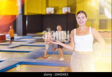 Young female sports instructor inviting to trampoline school Stock Photo