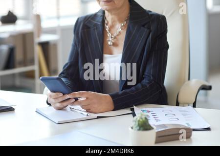 Close up of female boss using smartphone at workplace in office, copy space Stock Photo