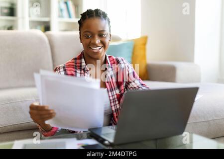 Positive pretty black lady entrepreneur working from home Stock Photo