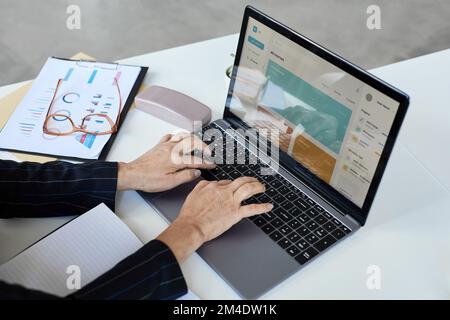 Close up of unrecognizable senior woman typing at laptop keyboard while working in office, copy space Stock Photo