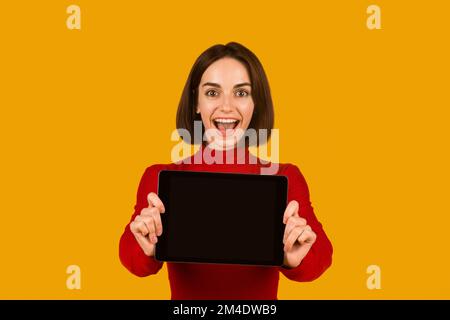 Excited attractive lady showing digital tablet with blank screen Stock Photo