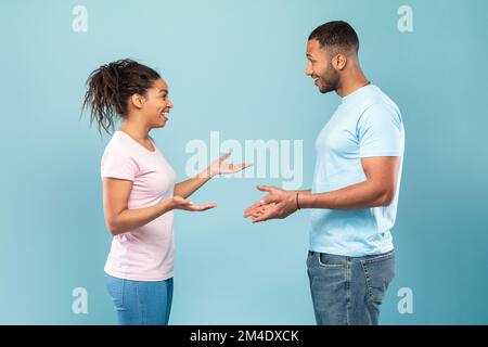 Communication. Profile portrait of black woman and man talking and gesturing over blue studio background Stock Photo