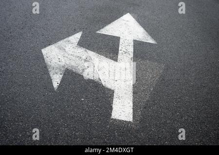 Arrow on asphalt showing direction. Grey background with a direction sign Stock Photo