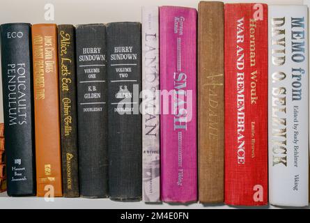 NEW ORLEANS, LA, USA - DECEMBER 8, 2022: Assortment of horizontally stacked 20th century books on the shelf in a personal library Stock Photo