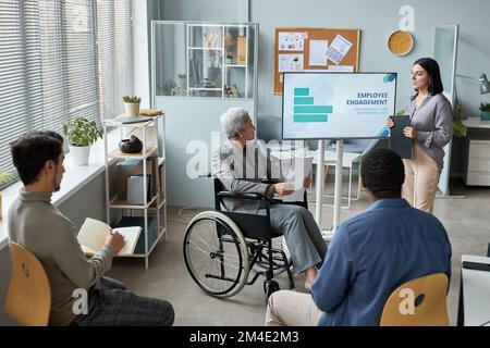 Portrait of mature woman using wheelchair while giving presentation in business meeting Stock Photo